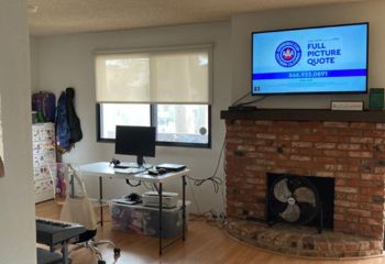 Home workspace in the living room featuring elegant pull down window shades and a bright, airy ambiance.