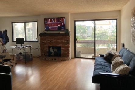 Living room displaying custom sheer roller shades on large windows and sliding glass door, adding style and natural light.